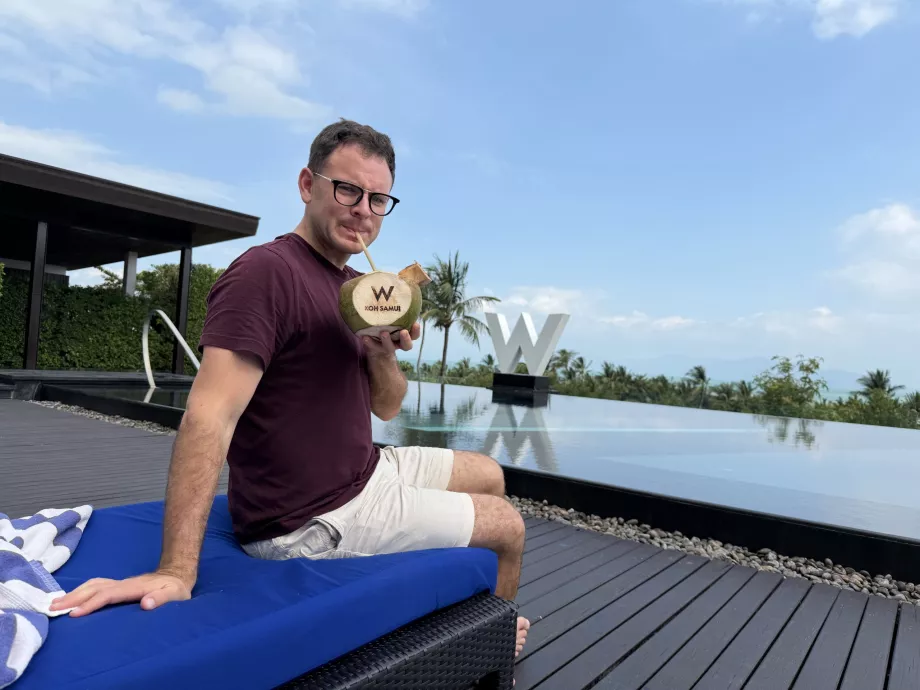 Moi avec une noix de coco gravée de la lettre "W" au bord de la piscine