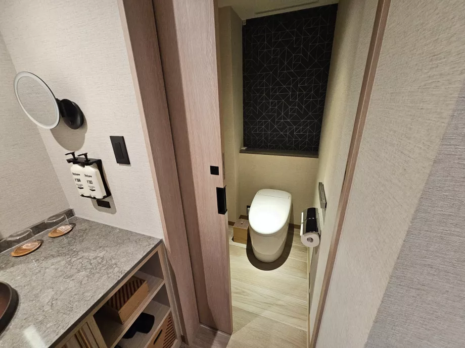 Toilettes séparées du reste de la salle de bains par une porte